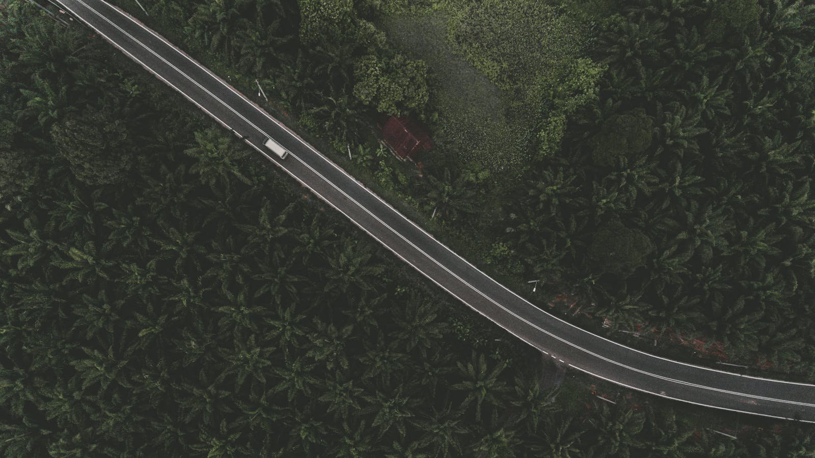 Aerial view of a highway cutting through lush tropical forest in Slim River, Malaysia.